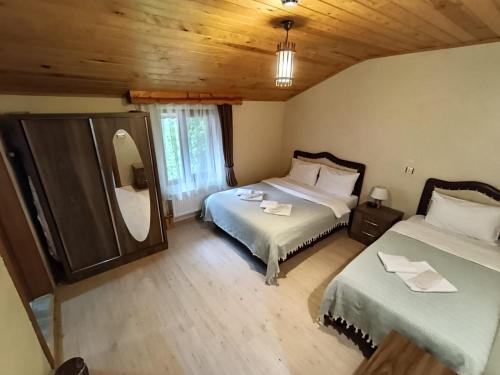 a bedroom with two beds and a mirror in it at Long Lake pansiyon in Uzungöl