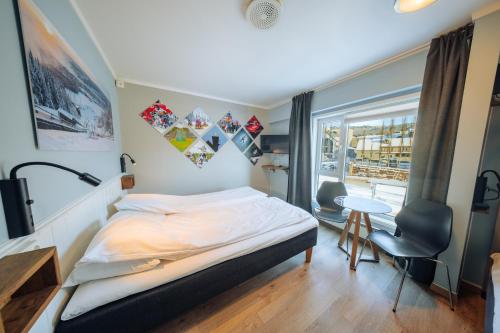 a bedroom with a bed and a table and a window at Stasjonen Hotel Lillehammer in Lillehammer