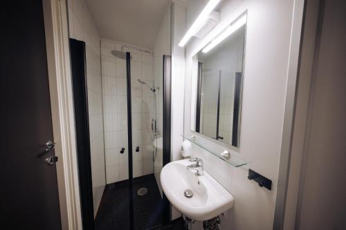 a white bathroom with a sink and a shower at Stasjonen Hotel Lillehammer in Lillehammer