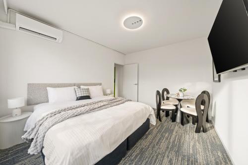 a bedroom with a bed and a table and chairs at Canvas On Barkly Apartments St Kilda in Melbourne