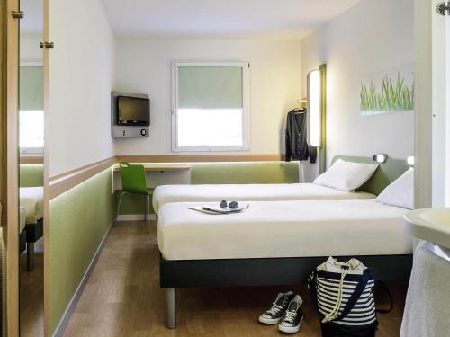 a hotel room with two beds and a tv at Ibis Budget Rambouillet in Rambouillet