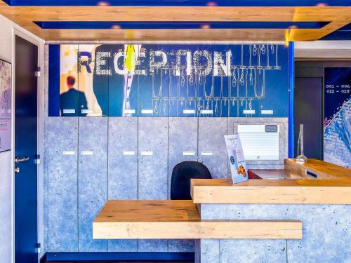 a restaurant with a wooden counter and a blue wall at ibis budget Issoire in Issoire