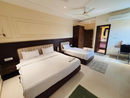 a hotel room with two beds and a chair at Hotel Corporate in Shivpurī
