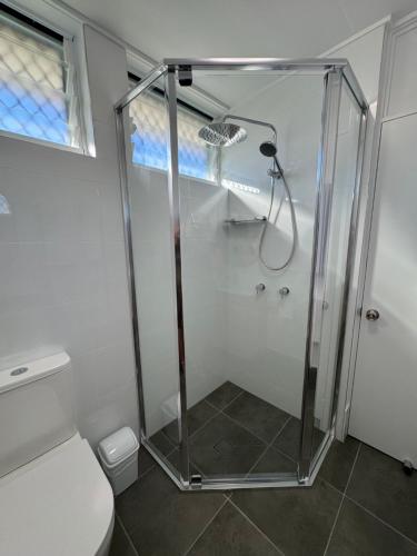 a shower stall in a bathroom with a toilet at Pearly Shell Motel in Bowen