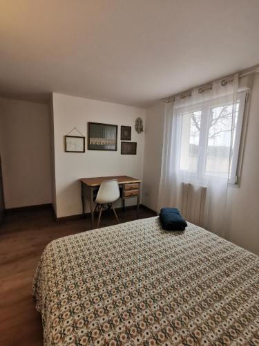a bedroom with a bed and a desk and a window at Dépendance avec jardin privé et vue sur campagne in Puydaniel