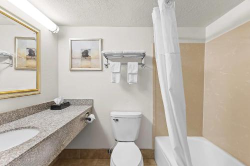 a bathroom with a toilet and a sink and a tub at Quality Inn Evanston near Wyoming Downs in Evanston