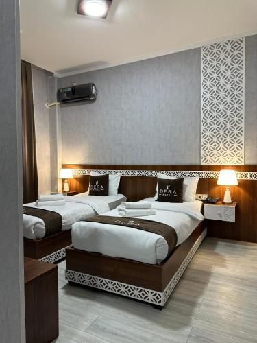 two beds in a hotel room with two lamps at Hotel Dera Bukhara in Bukhara