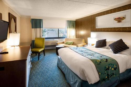 ein Hotelzimmer mit einem großen Bett und einem Stuhl in der Unterkunft Radisson Hotel Corning in Corning