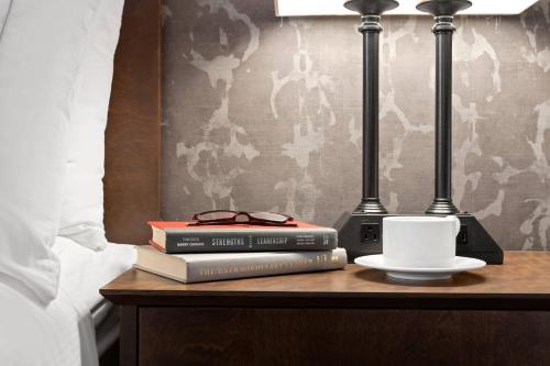 Ein Tisch mit zwei Büchern, einer Tasse und zwei Lampen in der Unterkunft Radisson Hotel Corning in Corning