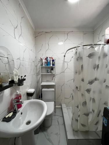 a white bathroom with a toilet and a sink at Diamond Resort Cottage Issyk-Kul in Bosteri