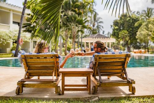 two women sitting at a table in chairs by a pool at Diamonds Malindi in Malindi