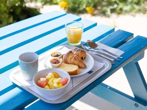 a plate of breakfast food on a blue picnic table at Ibis Budget Marmande in Marmande