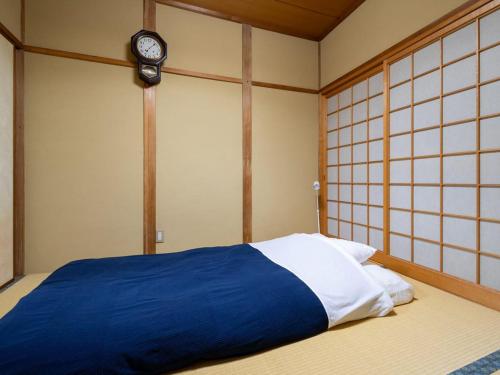 a bedroom with a bed with a clock on the wall at Gallery NICO Osaka Yao in Yaochō