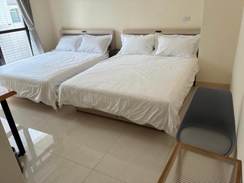 two beds with white sheets in a room with a chair at Green Home in Yuli