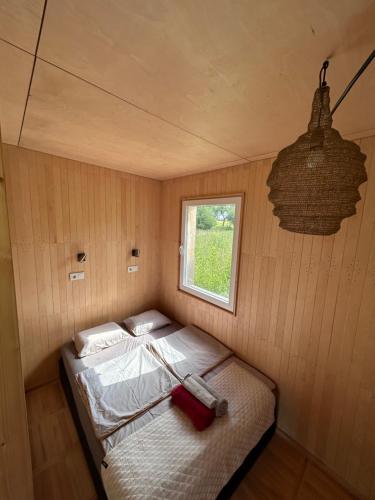 a small bed in a room with a window at Pagalėlių namai in Voveriai
