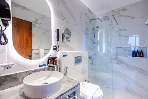 a white bathroom with a sink and a mirror at فندق كورنيت النورس - جدة in Jeddah