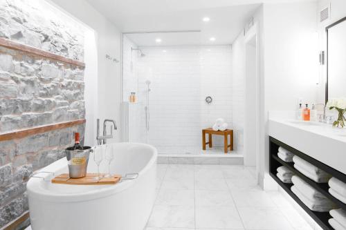 a white bathroom with a tub and a shower at Frontenac Club, an Ascend Collection Hotel in Kingston