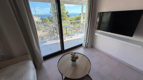 a living room with a table and a large window at Golden Evelyn in Agia Paraskevi