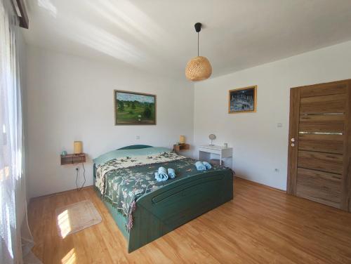 a bedroom with a green bed and a wooden floor at Kuća za odmor Dankica in Veliko Trgovišće