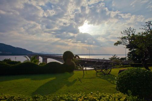 a statue in a park with a bridge in the background at Champasak Grand Hotel in Pakse