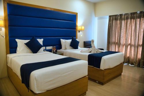 two beds in a hotel room with a blue headboard at Peerless Hotel Hyderabad in Hyderabad