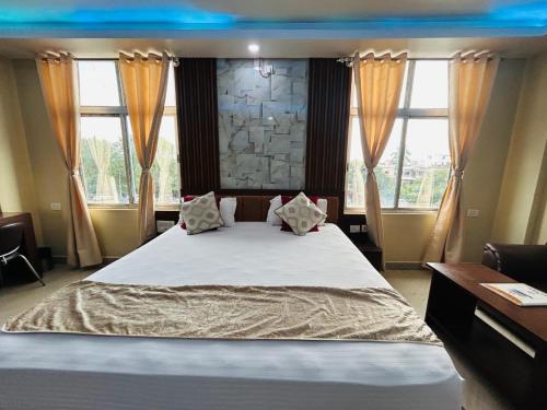 a bedroom with a large white bed with windows at Hotel Sky View in Aurangābād