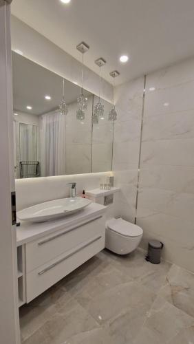 a white bathroom with a sink and a toilet at Villa Las Palmas in Strzeszów