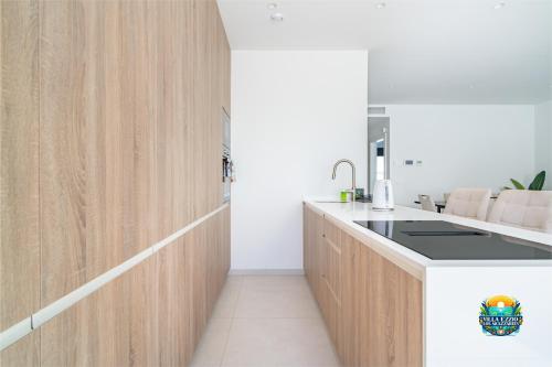 a kitchen with wooden cabinets and a sink at Villa Ezzio Los Alcazares in Los Alcázares