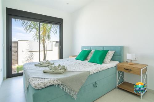 a bedroom with a bed with green pillows and a window at Villa Ezzio Los Alcazares in Los Alcázares