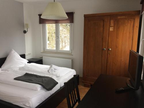 Schlafzimmer mit einem Bett mit weißer Bettwäsche und einem Fenster in der Unterkunft Pension Glücklich in Horgenzell