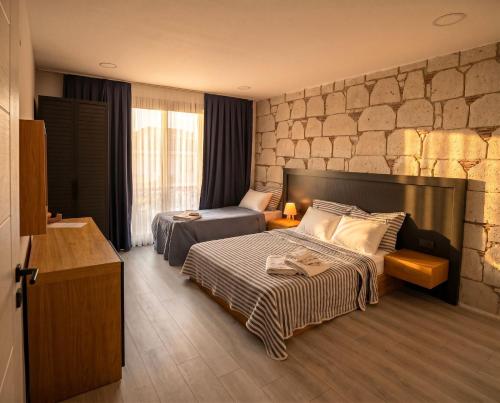 a bedroom with two beds and a stone wall at Kiva Alaçatı Hotel By Amarillo in Çeşme