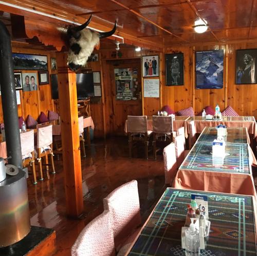 a dining room with two tables and a cow head on the wall at Hotel Khangri in Namche