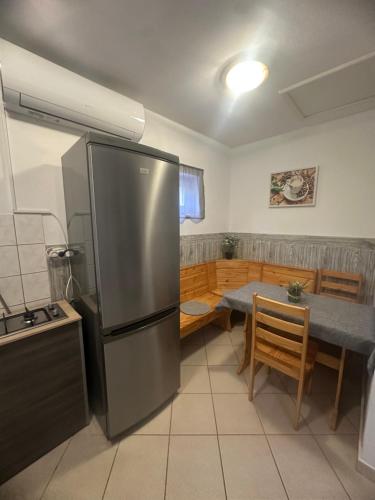 a kitchen with a stainless steel refrigerator and a table at Gréta Apartman in Ábrahámhegy