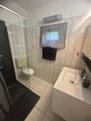 a bathroom with a toilet and a sink and a shower at Gréta Apartman in Ábrahámhegy