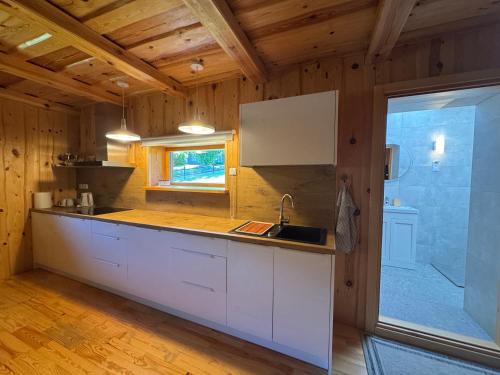 a kitchen with white cabinets and a large window at Stripeikių Bitė in Varniškės I