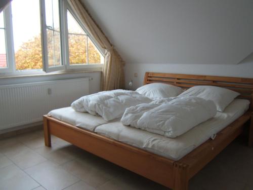 a bed with white pillows on it in a room with windows at Ferienwohnung SEEWOLF im Herzen von Zingst in Zingst