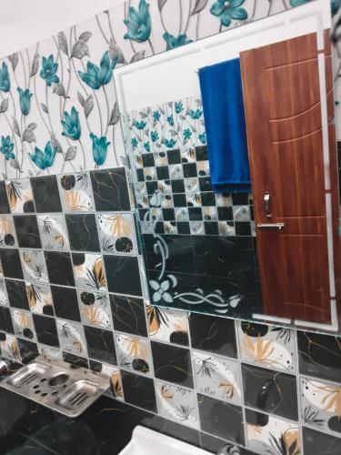 a bathroom with a black and white tiled wall at Jungle Valley Camp & Resort in Nainital