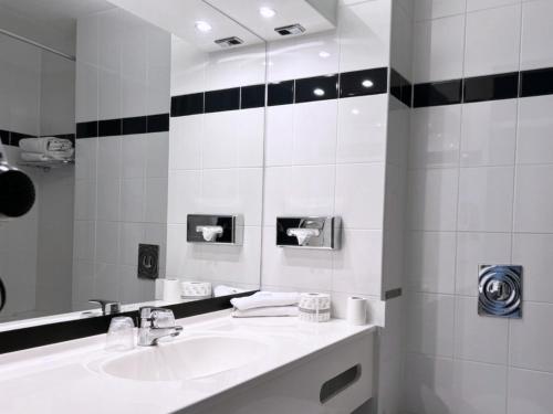 a white bathroom with a sink and a mirror at A-Hotel Oosterhout in Oosterhout