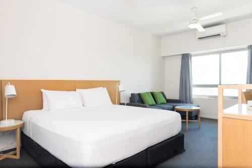 a bedroom with a large white bed and a couch at Darwin Harbour Sunset Views in Darwin