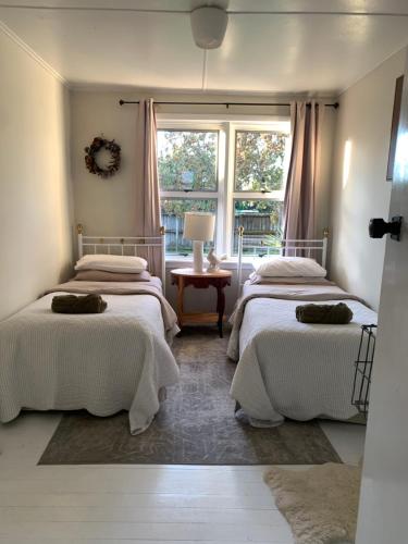 two beds in a room with a window at Cooper's Cottage in Nelson