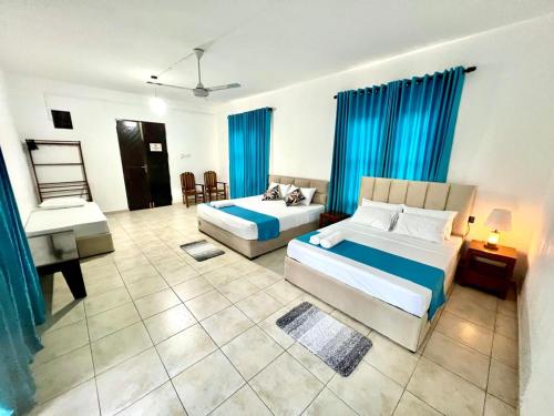 a bedroom with two beds and blue curtains at Hotel One Sixty in Dehiwala