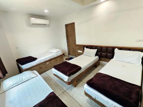 a room with three beds in a room at Hotel Milan in Ahmedabad