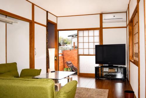 a living room with a tv and a green couch at Komorebi/こもれび in Takayama