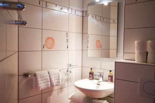 a white bathroom with a sink and a mirror at Eiger Guest House - Grindelwald in Grindelwald