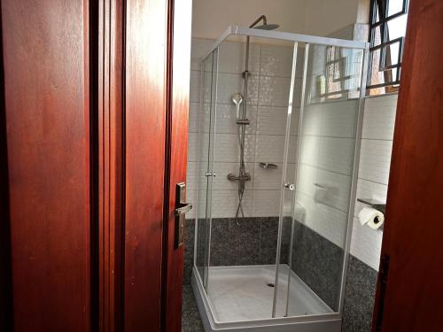 a shower with a glass door in a bathroom at El SALI APARTMENTS in Buwate