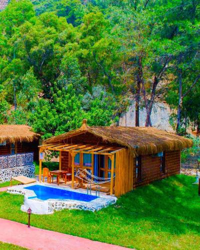 a small house with a thatch roof and a swimming pool at Gizli Cennet Villages Hotel in Fethiye