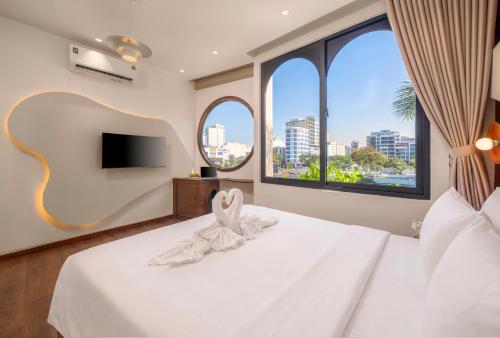 a bedroom with a white bed with a tv and windows at Vista Del Sol Hotel in Danang