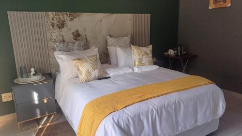 a bedroom with a large bed with white sheets and pillows at Mangena Legacy Guesthouse in Polokwane