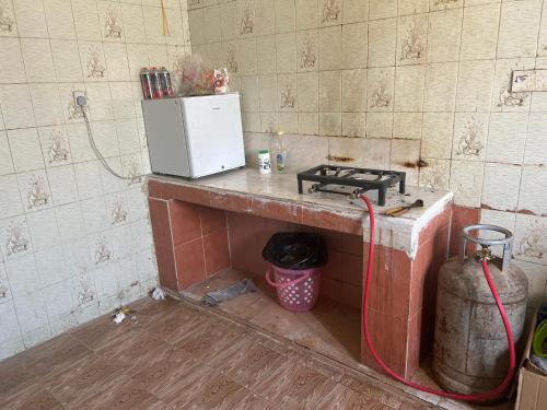 a kitchen with a counter with a stove and a refrigerator at Beach hostel in Muscat