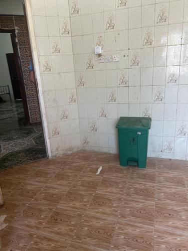 a room with a green trash can on a tile floor at Beach hostel in Muscat